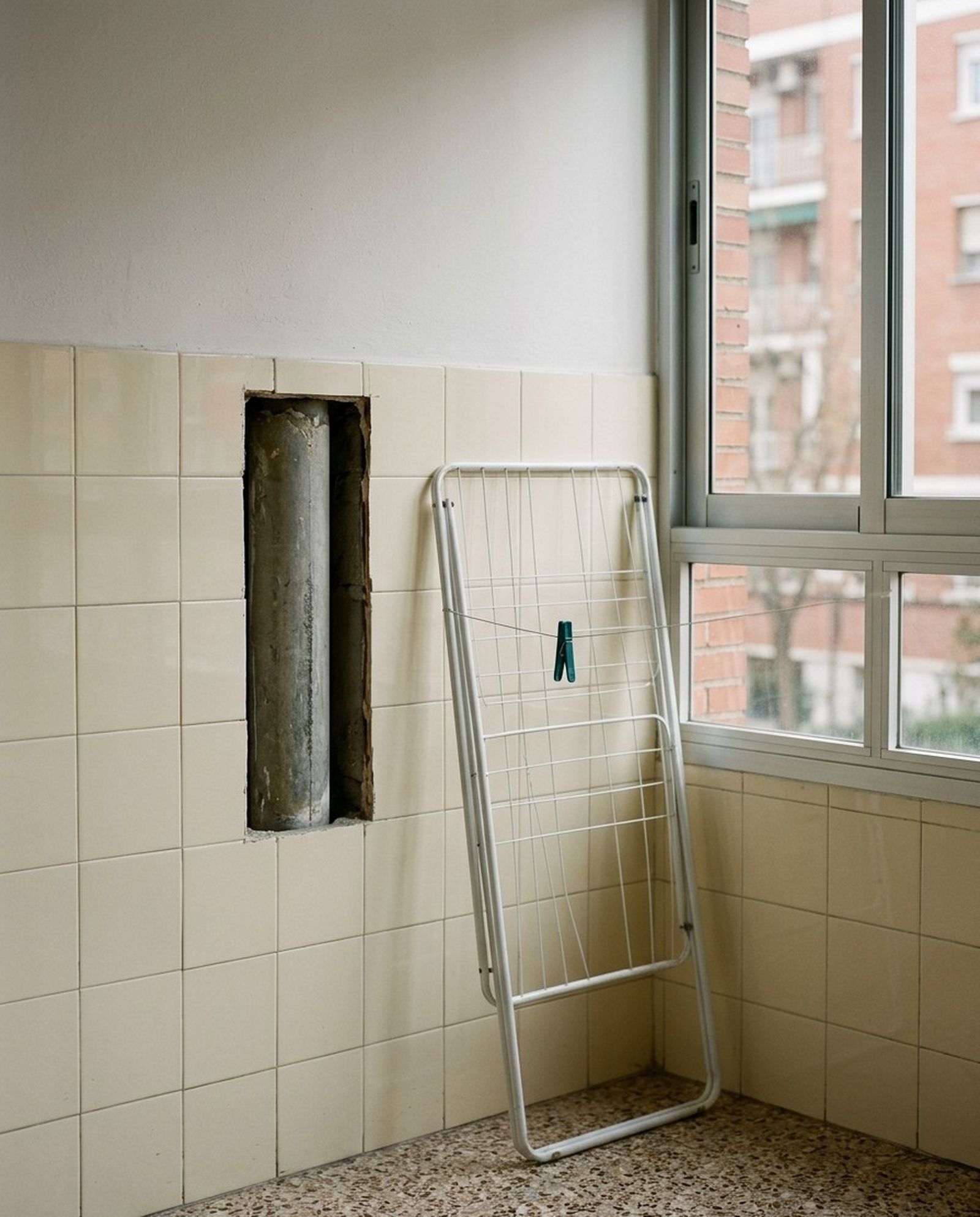 Bajante de fibrocemento gris en la pared de una galería tendedero, vista por un registro abierto