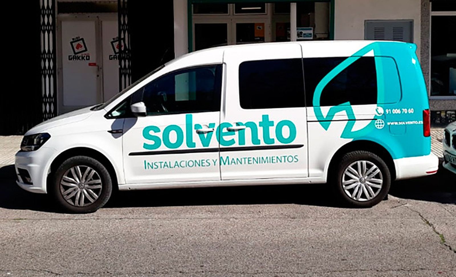 Furgoneta de Solvento rotulada con la marca y el teléfono, aparcada delante de la oficina